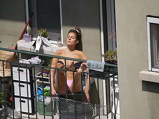 Unaware girl gets some sun on the balcony 