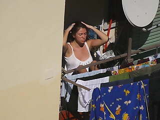 Busty girl enjoying the sun on the balcony 