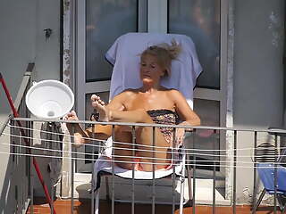 Blonde granny sunbathing on the balcony