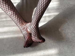Girl in black fishnet pantyhose caresses her legs